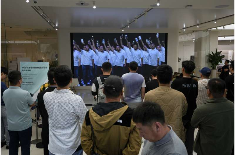 Customers watch a screen broadcasting live of Huawei staff wave with Huawei Mate 60 series smartphones during the Huawei new product launch conference at a Huawei store in Beijing, on Sept. 25, 2023. Chinese telecoms equipment maker Huawei Technologies has reported its profit inched higher in the first three quarters of this year despite persisting U.S. sanctions that have hindered both its sales and its purchases of advanced technology.Credit: AP Photo/Andy Wong, File Huawei reports its revenue inched higher in January-September despite US sanctions