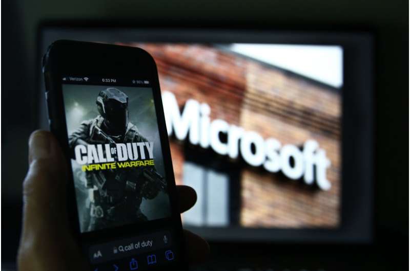 An image from Activision's Call of Duty is shown on a smartphone near a photograph of the Microsoft logo in this photo taken in New York, June 15, 2023. Microsoft’s purchase of video game maker Activision Blizzard won final approval Friday, Oct. 13, from Britain’s competition watchdog, reversing its earlier decision to block the $69 billion deal and removing a last obstacle for one of the largest tech transactions in history. Credit: AP Photo/Peter Morgan, File Microsoft spent two years trying to buy Activision Blizzard. For Xbox CEO, that was the easy part