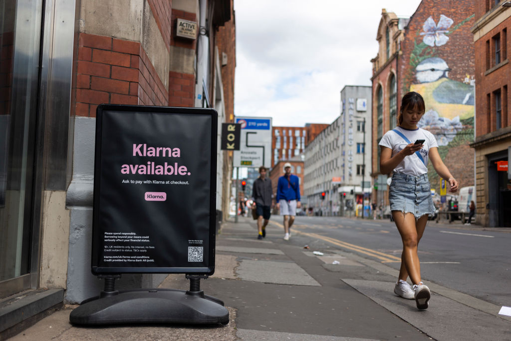 Members of the public pass by a floor advertisement for tech firm Klarna.