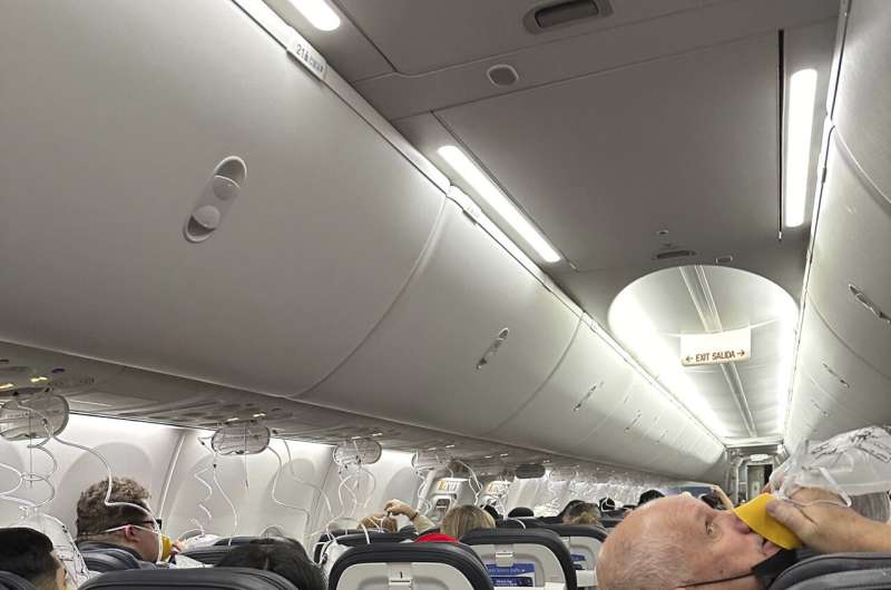 This image provided by Kelly Bartlett shows passengers with oxygen masks on an Alaska Airlines Boeing 737 Max 9, Flight 1282, which was forced to return to Portland International Airport on Friday, Jan. 5, 2024. Credit: Kelly Bartlett via AP Investigation into why a panel blew off a Boeing Max 9 jet focuses on missing bolts
