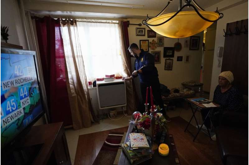 Lisa Mercado watches television as Daniel Melo, project manager for sustainability and energy programs for New York City Housing Authority, checks on a window-mounted heat pump in her apartment in the Queens borough of New York, on Thursday, Feb. 29, 2024. The heat pump, part of a pilot project by the NYCHA, is aimed at cutting energy costs and lowering emissions. Credit: AP Photo In New York City, heat pumps that fit in apartment windows promise big emissions cuts